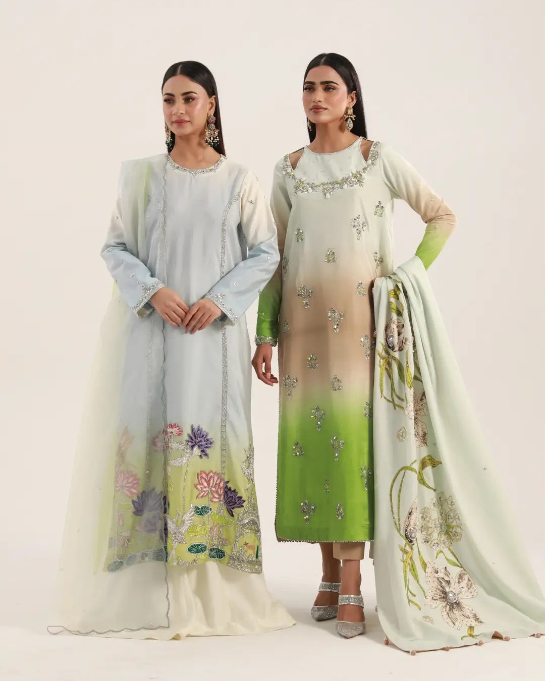 Two women modeling elegant embroidered Pakistani formal dresses with matching shawls and floral patterns.
