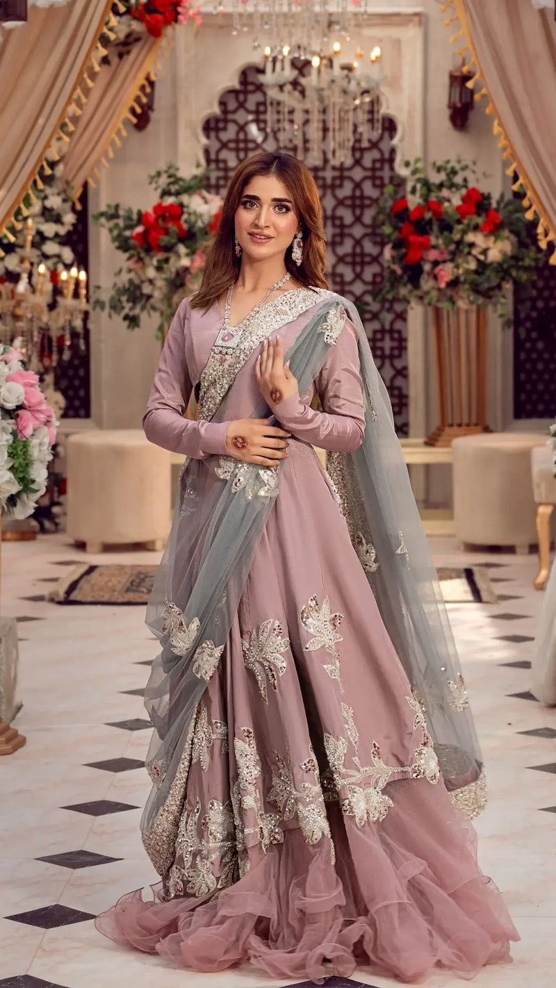 Woman wearing an embroidered mauve formal Pakistani dress with a dupatta, elegant indoor setting