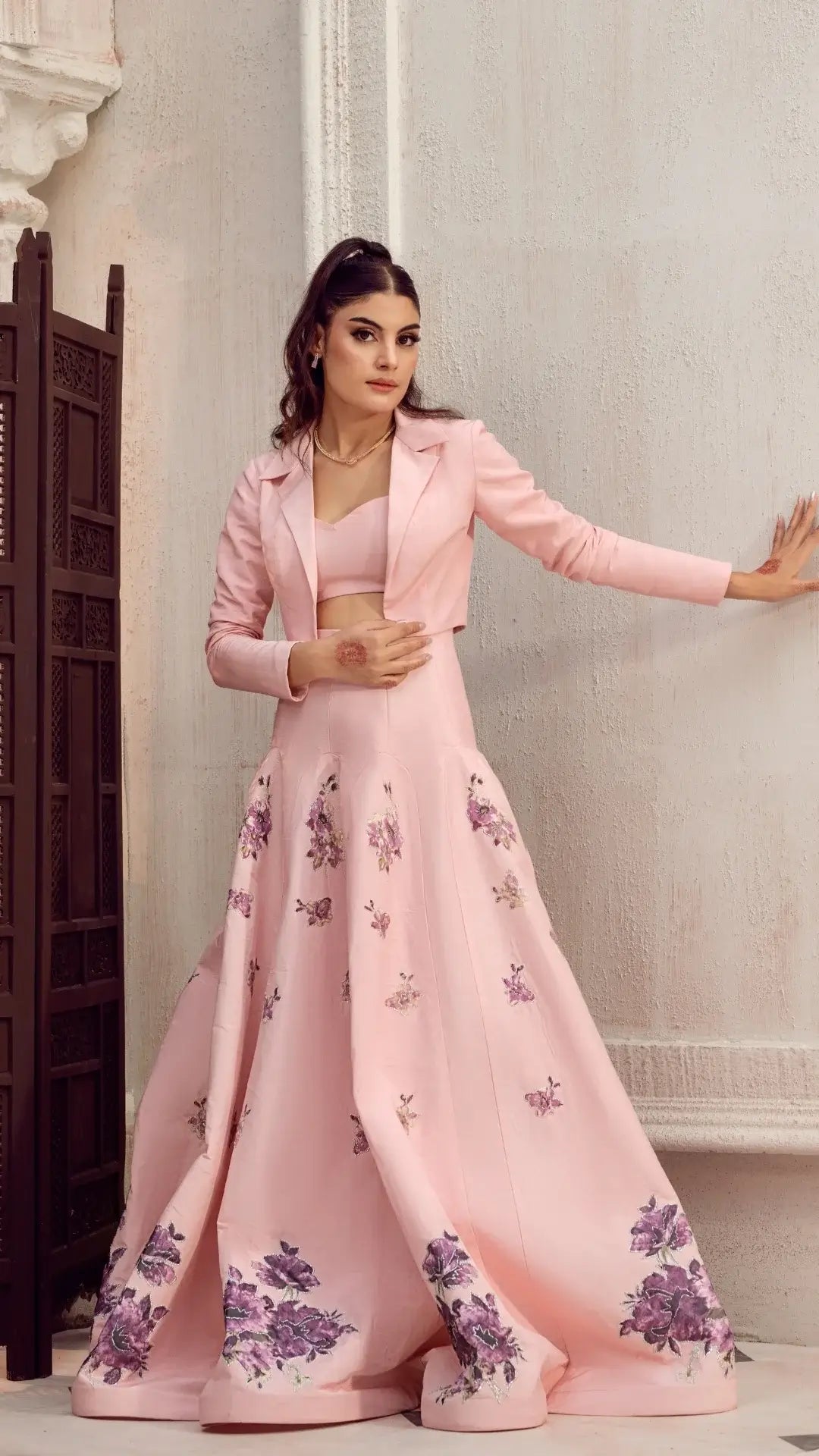 Woman wearing elegant light pink formal dress with floral embroidery and cropped blazer