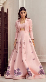 Woman wearing a light pink embroidered lehenga set with floral designs, formal Pakistani wear