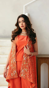 Woman wearing an orange outfit with a matching vest indoors.