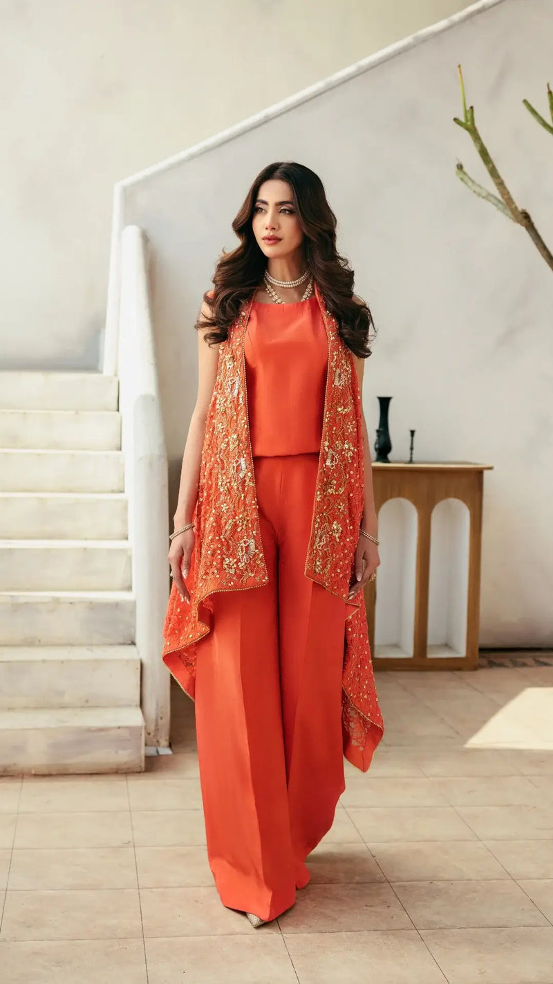 Woman in an orange outfit with a matching vest standing in a modern interior setting.