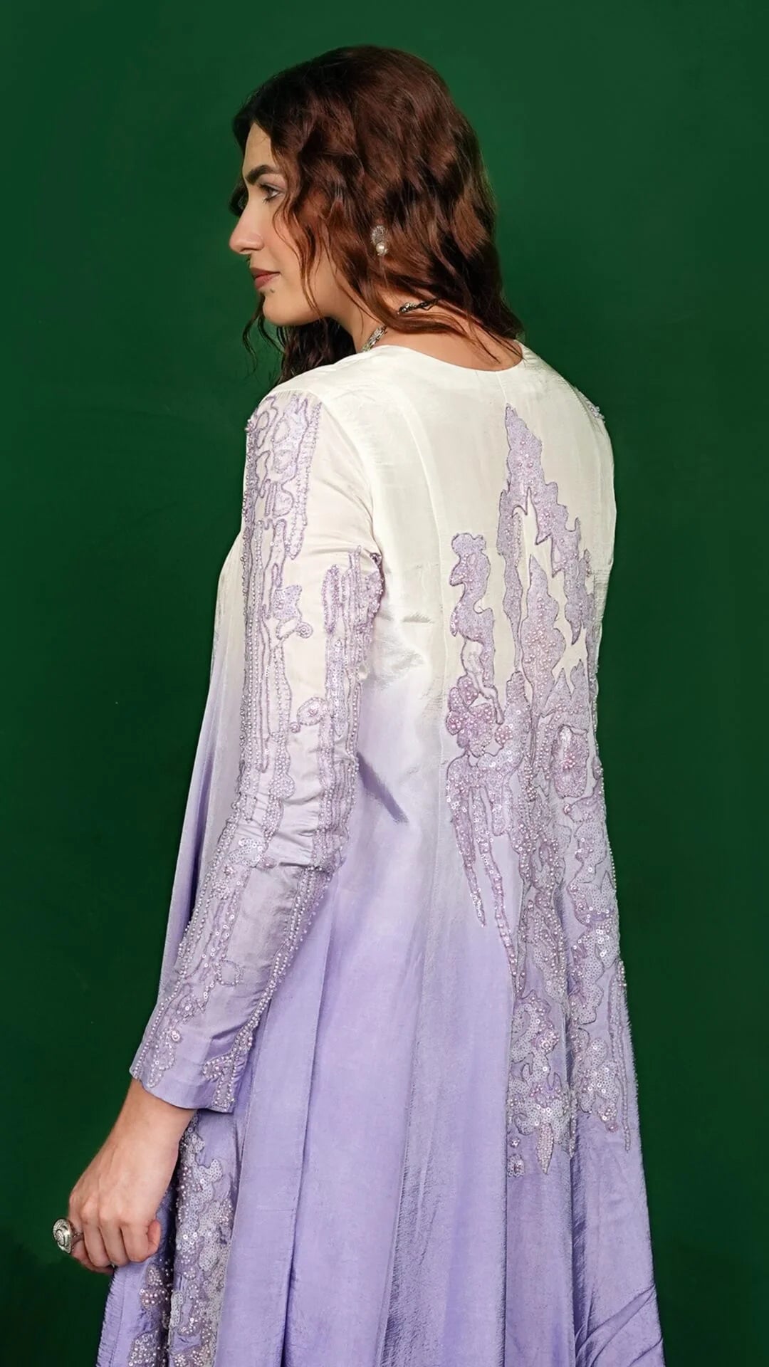 Woman wearing a light purple embroidered outfit against a green background