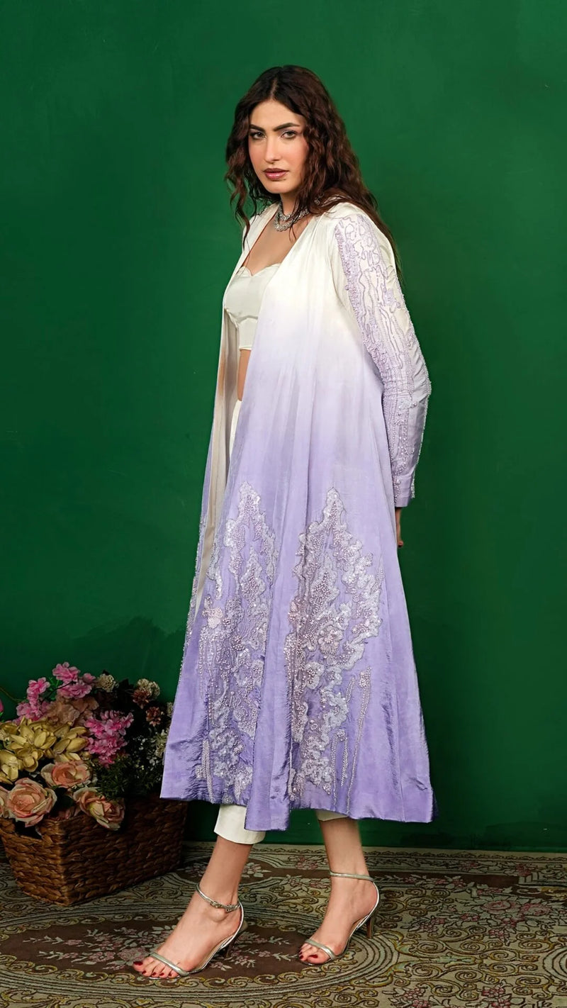 Woman wearing a light purple embroidered outfit against a green background