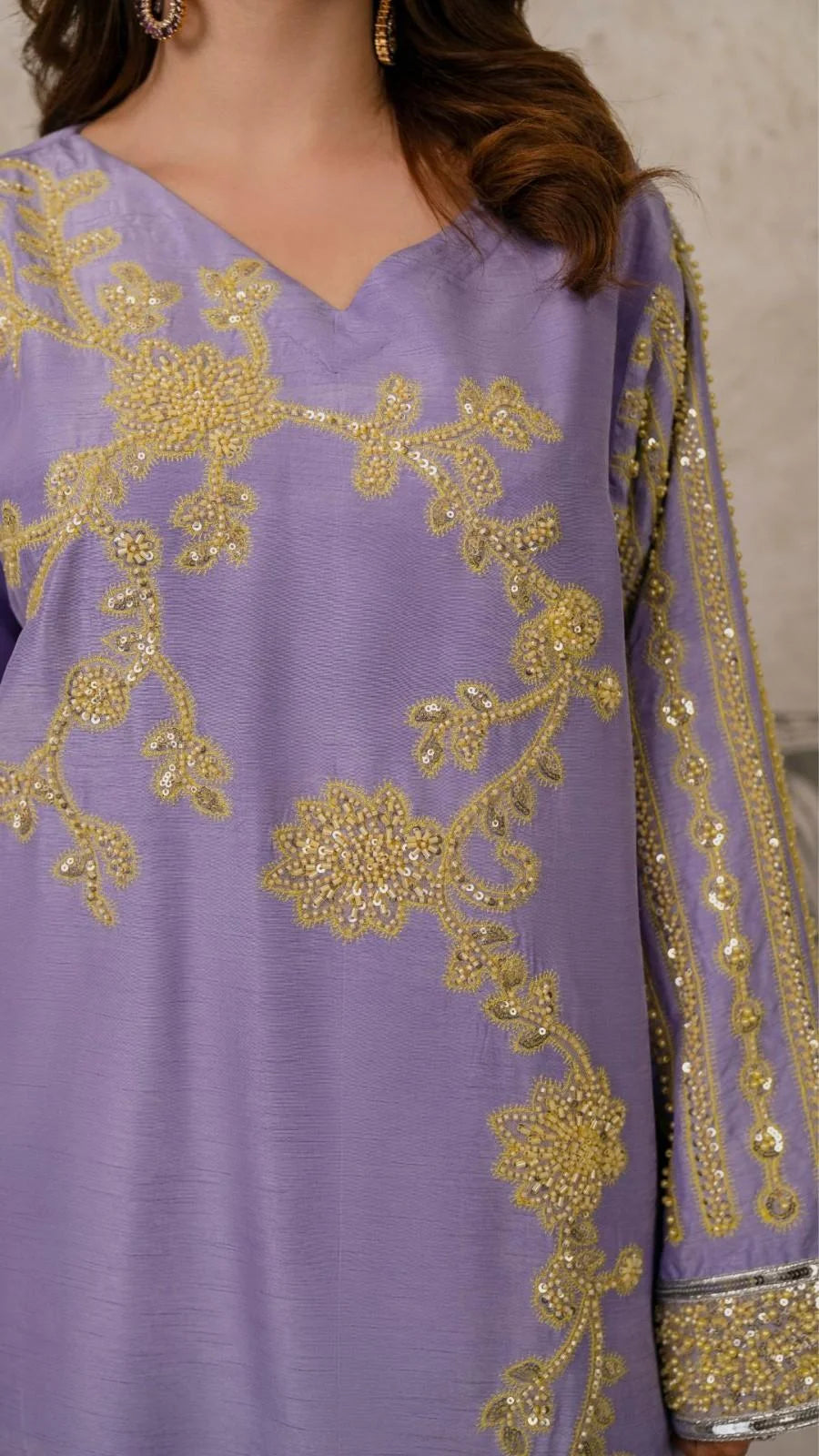 Purple outfit with gold embroidery on a neutral background