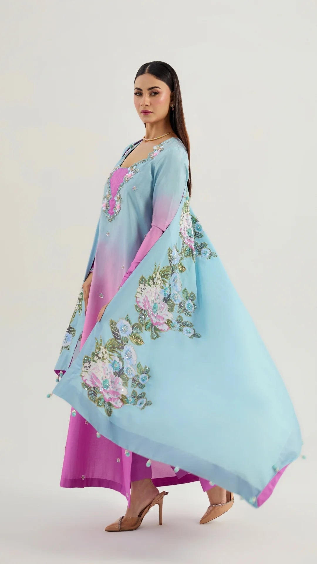 Woman wearing a light blue and pink floral dress with a matching dupatta on a white background