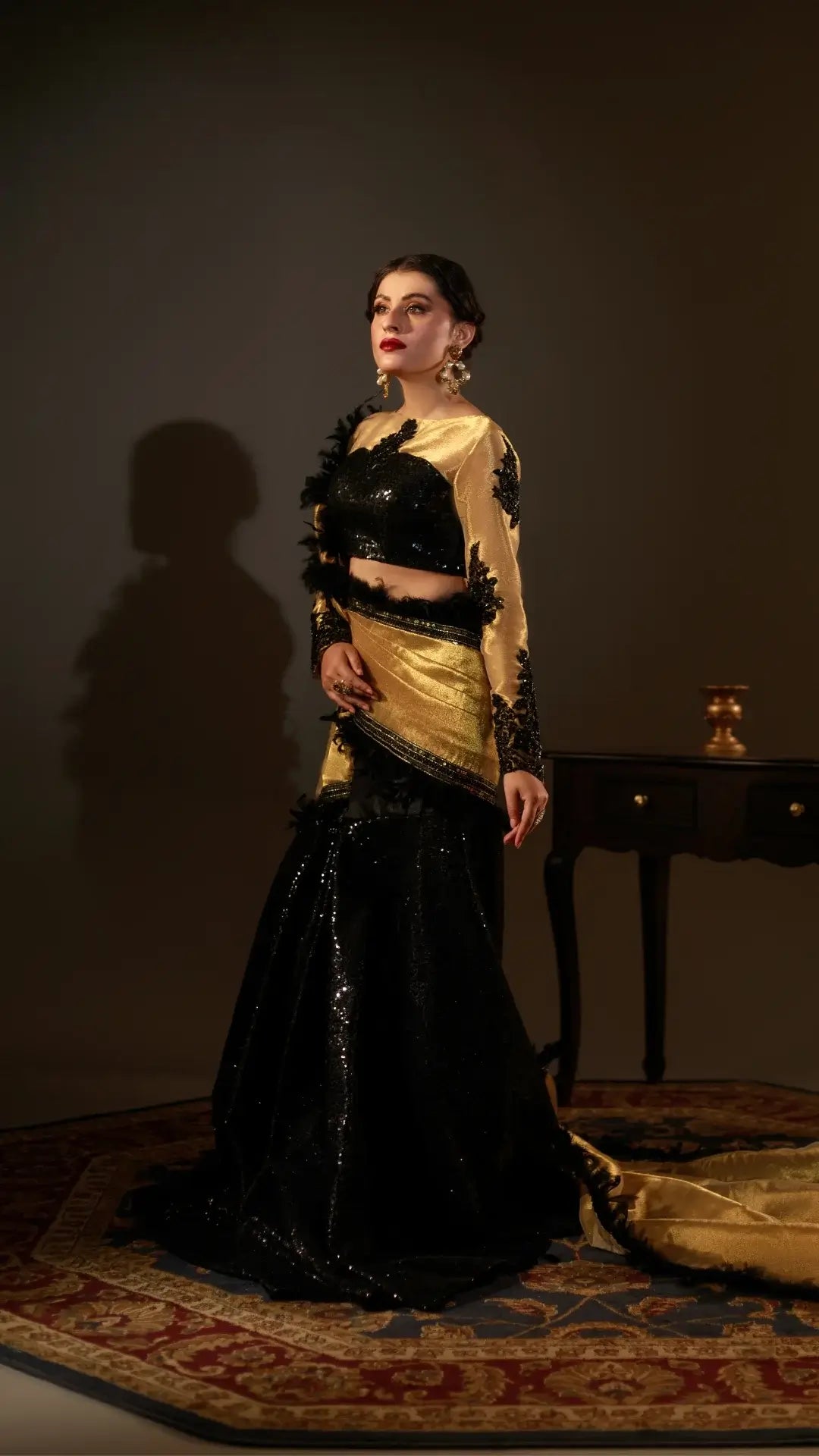 Woman in a black and gold traditional outfit standing against a dark background
