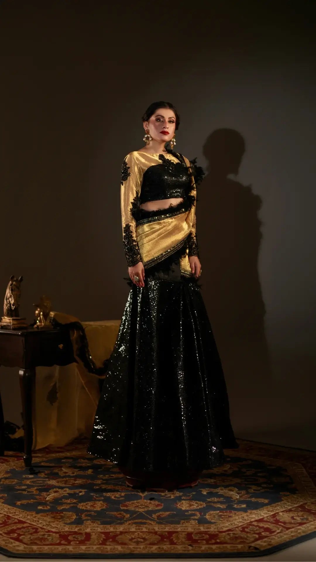 Woman wearing a black and gold traditional outfit in a dimly lit room.