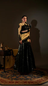Woman wearing a black and gold traditional outfit in a dimly lit room.