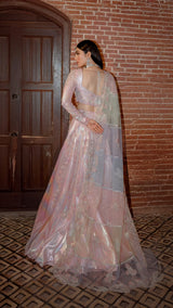 Woman in pastel pink embroidered formal lehenga with dupatta, standing by brick wall