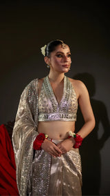 Woman in traditional silver and red outfit with jewelry against a dark background