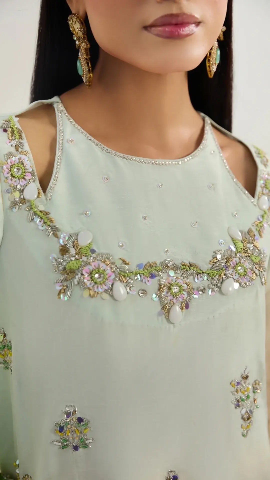 Light green outfit with floral embroidery and bead details on a plain background
