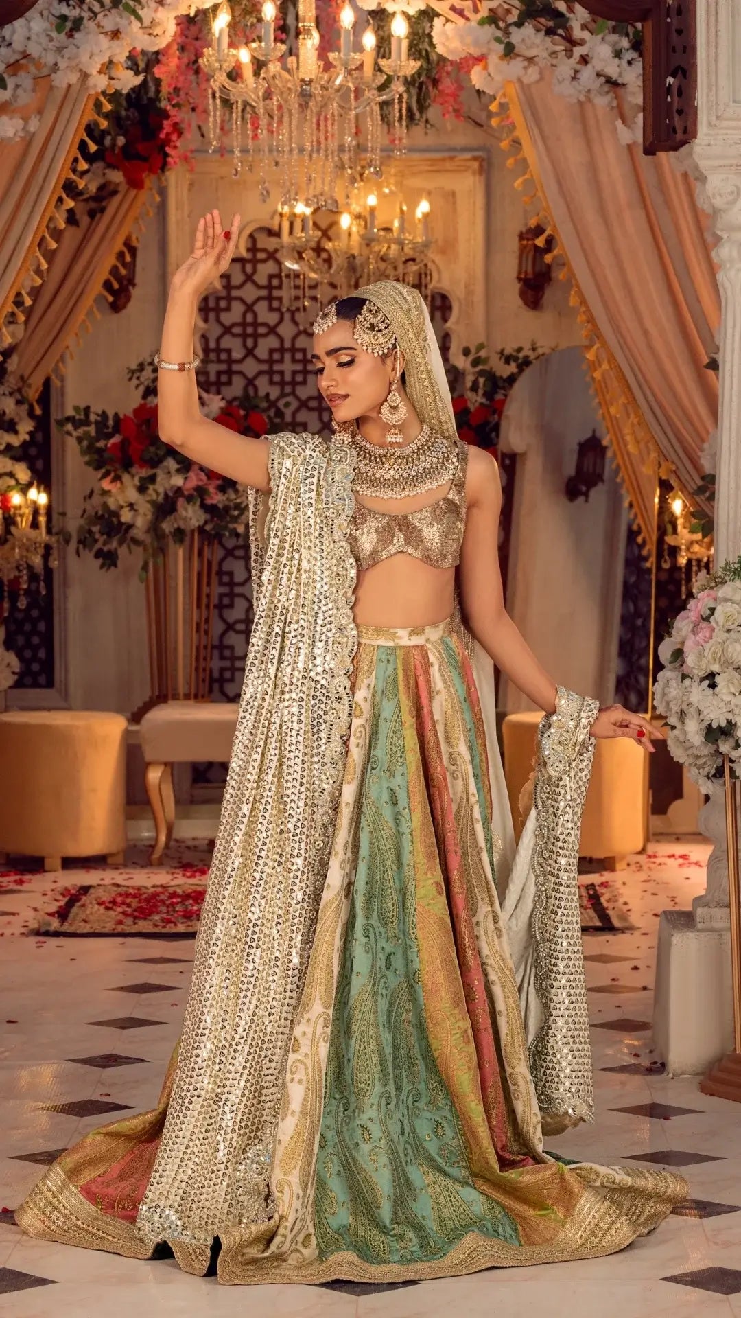 Woman in luxurious multicolor lehenga with gold embroidered dupatta and jewelry, in elegant indoor setting