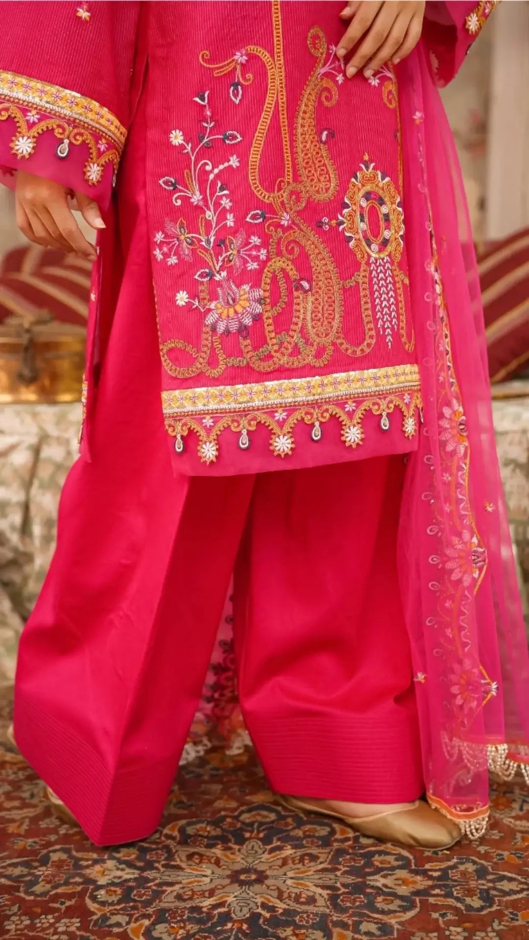 Traditional pink embroidered outfit with a matching dupatta on a patterned background