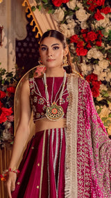 Woman in luxury fuchsia Pakistani formal dress with gold embroidery and floral jewelry, floral backdrop