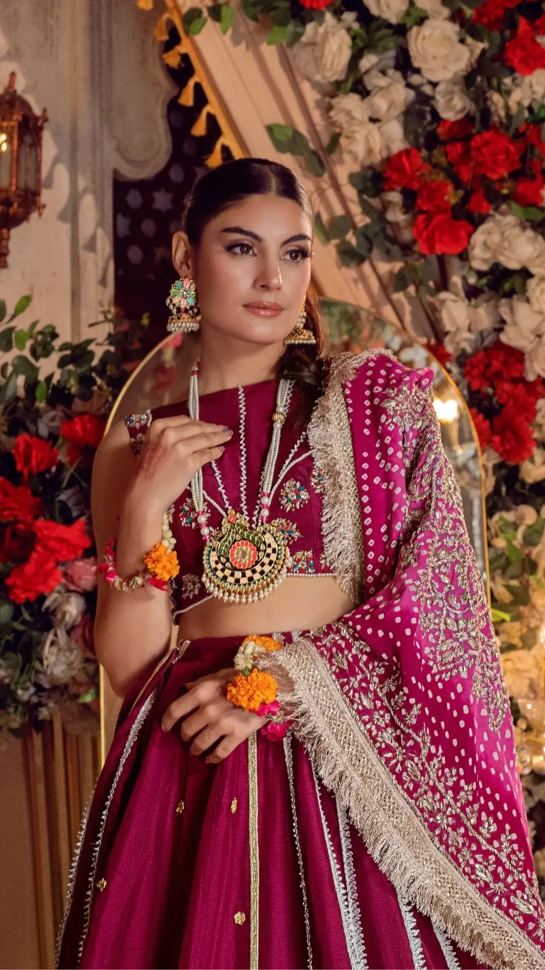 Woman in a traditional pink and red saree with floral decorations in the background