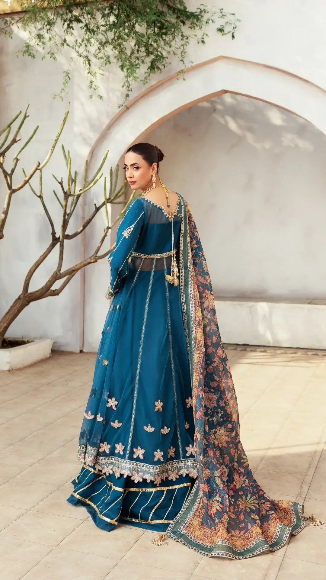Woman in a blue traditional outfit with floral patterns indoors.