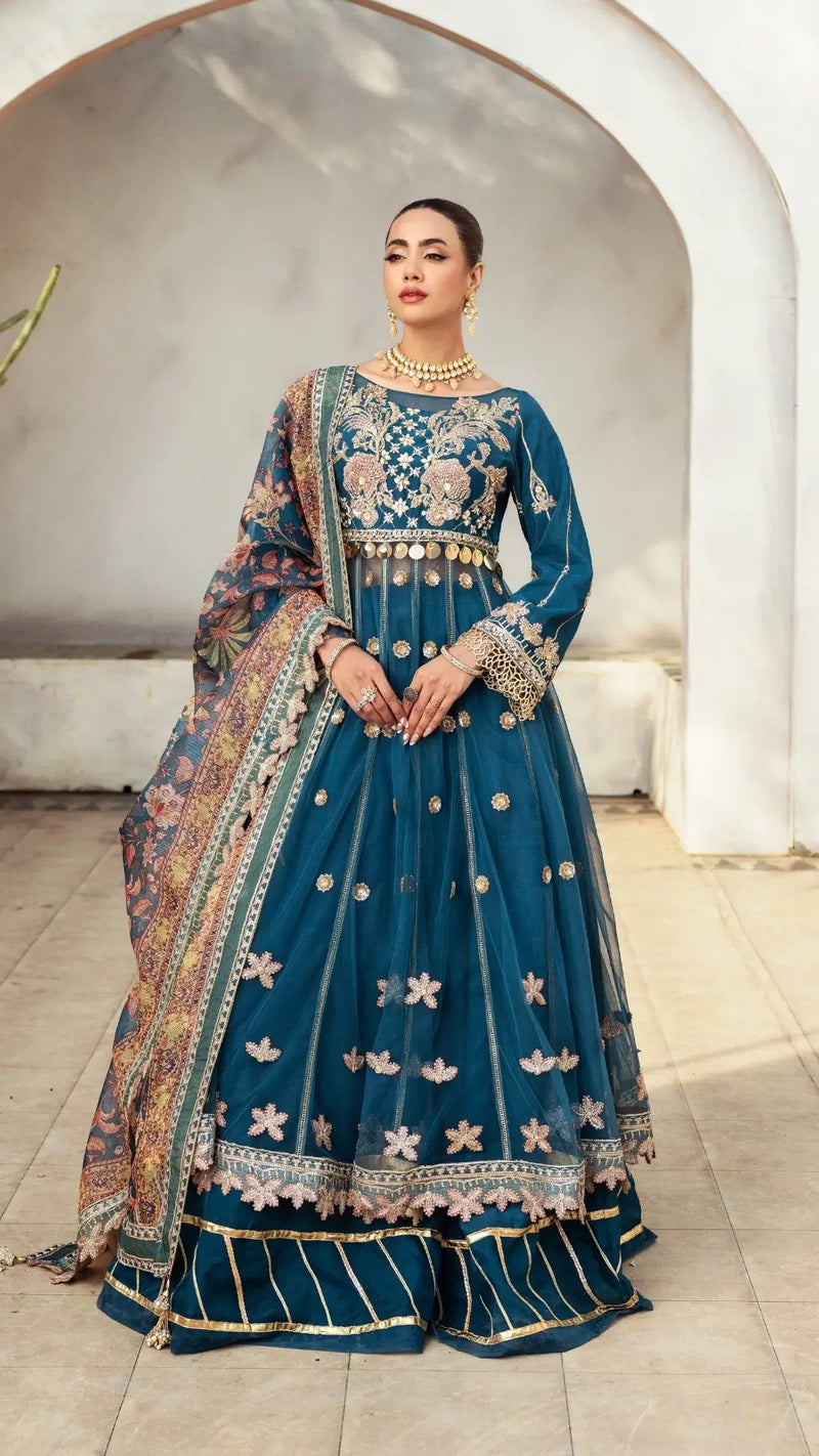Woman wearing a traditional blue embroidered outfit with gold details indoors.