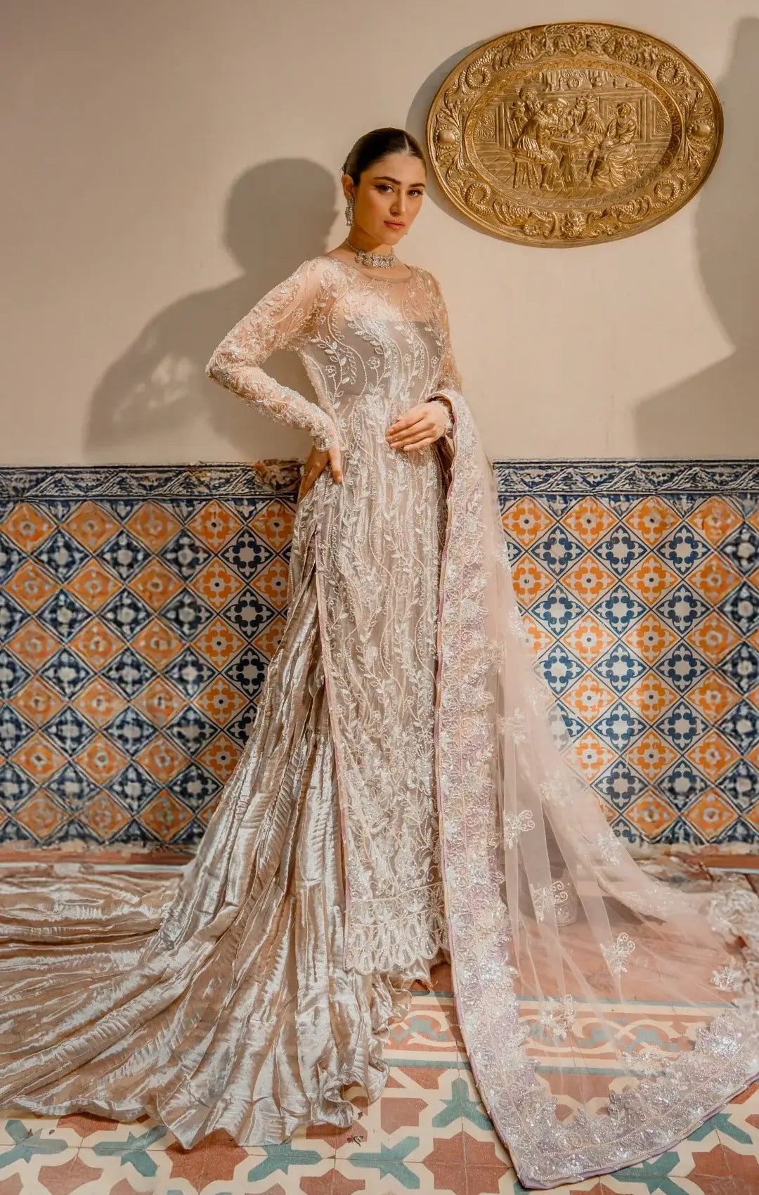Elegant ivory embroidered Pakistani formal dress with sheer sleeves, worn by a model indoors.
