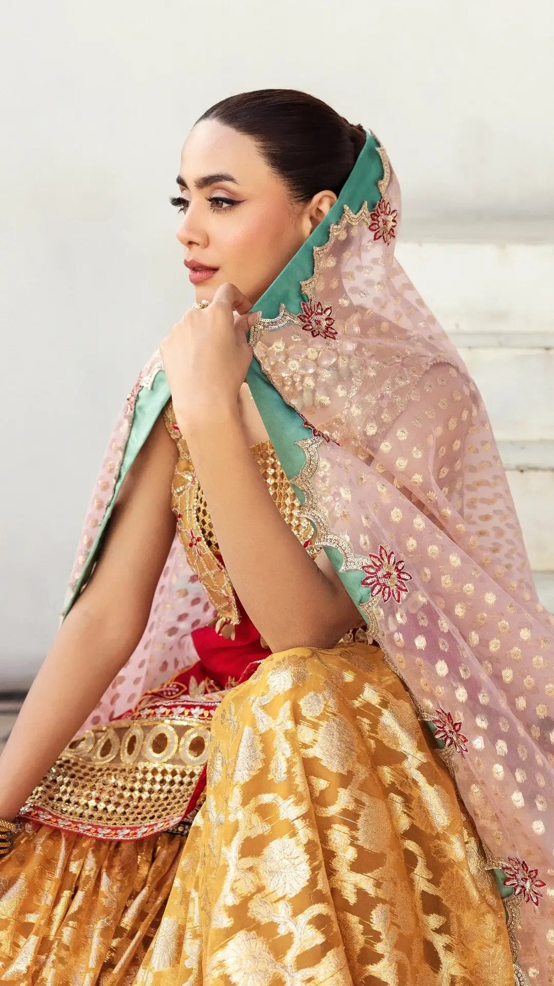 Woman in traditional outfit with gold and pink elements on a light background