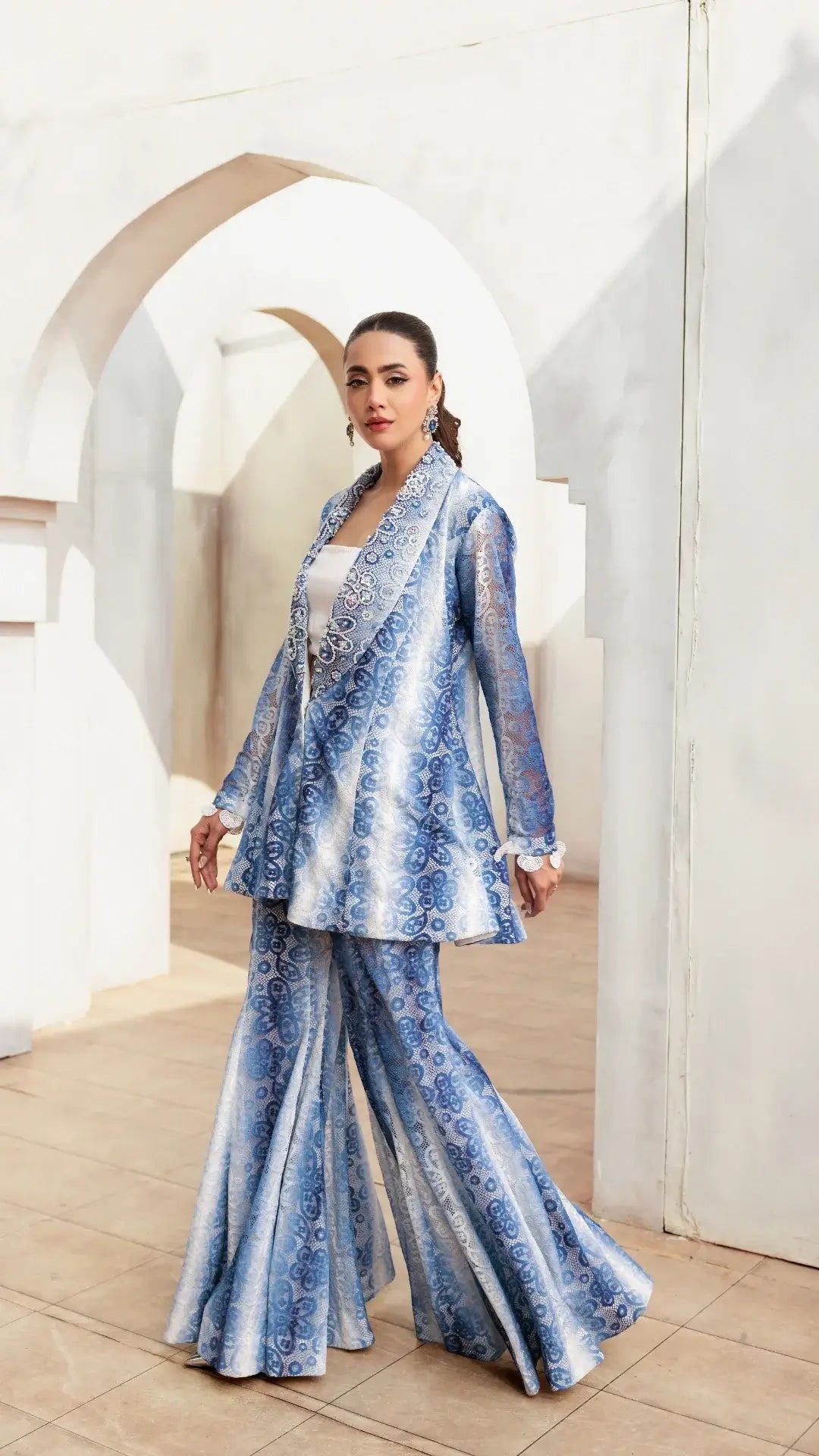 Woman wearing a blue and white patterned outfit in a bright room.