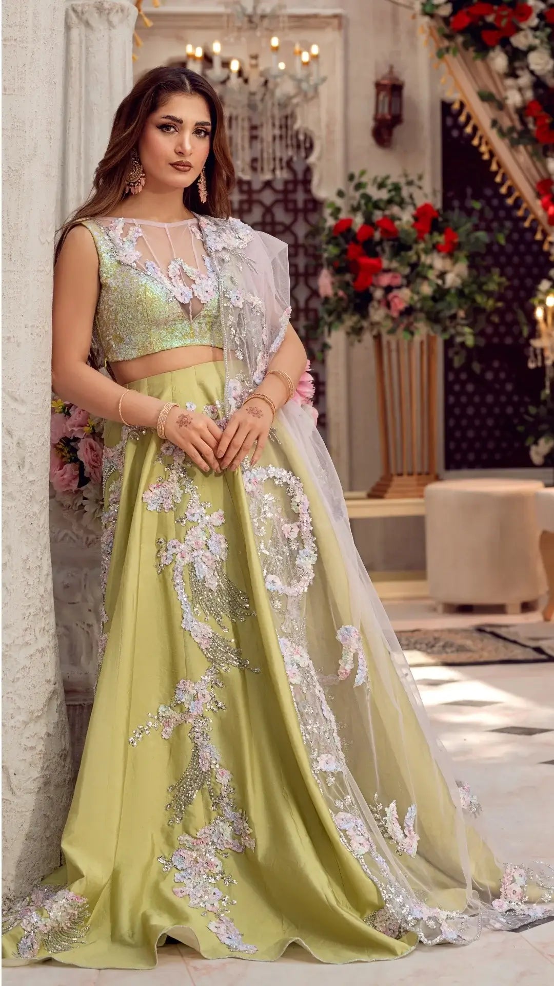 Woman wearing a green embroidered lehenga with a white dupatta in an indoor setting.
