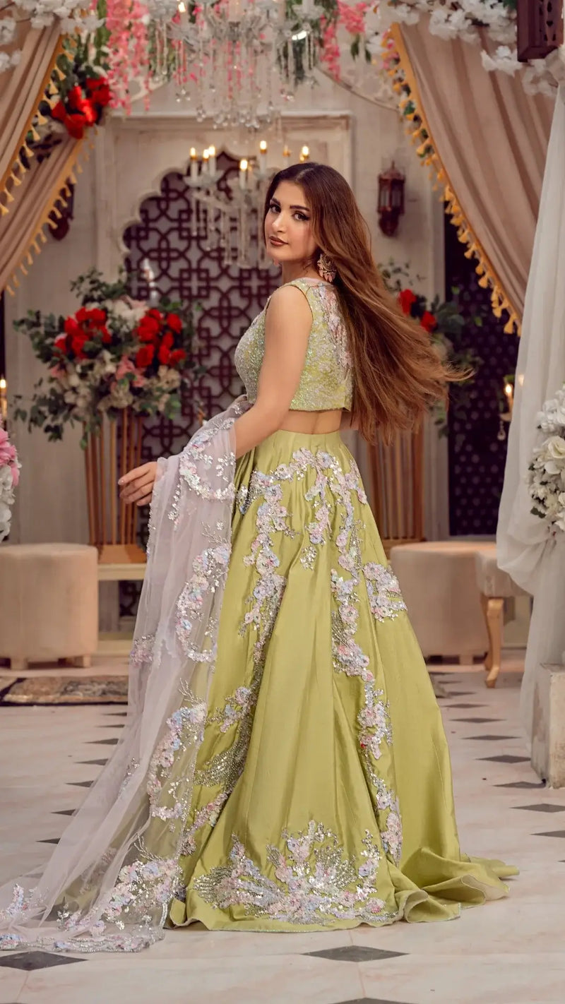 Woman in embroidered pastel green lehenga with sheer dupatta, formal party dress setting