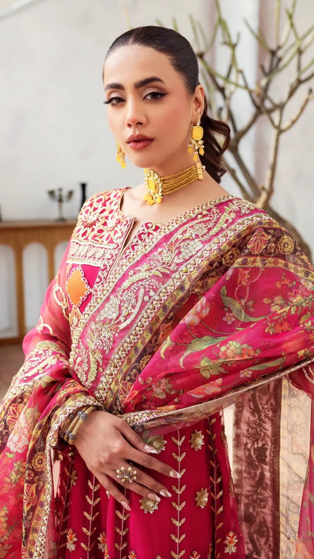 Woman in a traditional pink and gold embroidered saree indoors.