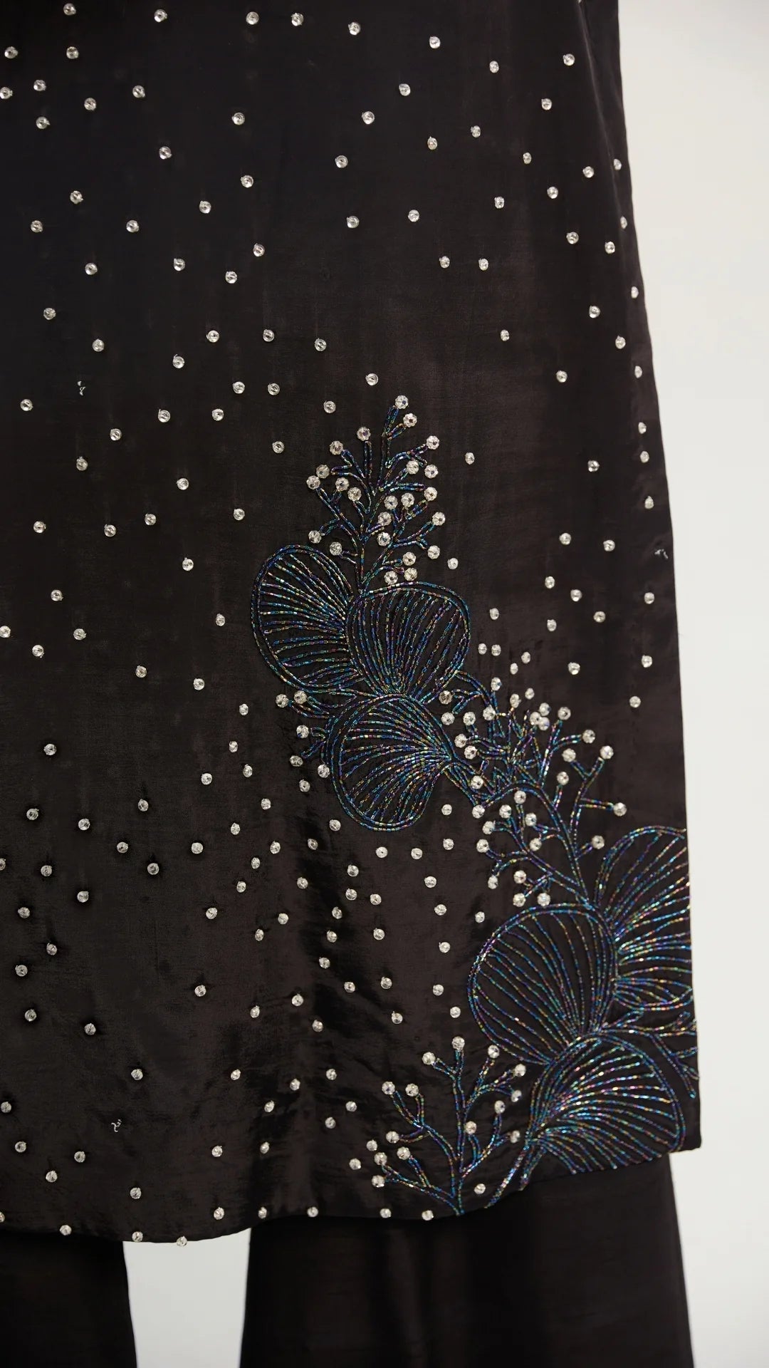 Black fabric with floral embroidery and bead detailing on a white background