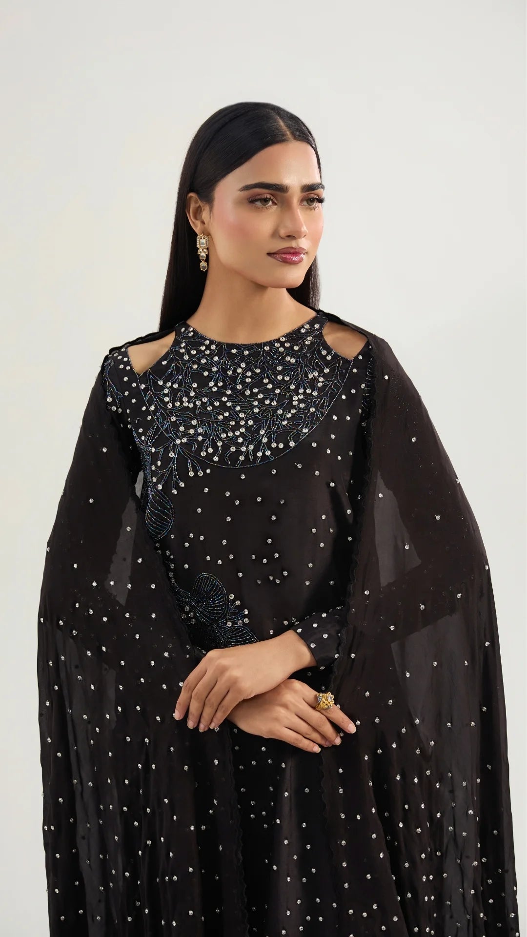 Woman wearing a black outfit with silver embellishments on a white background