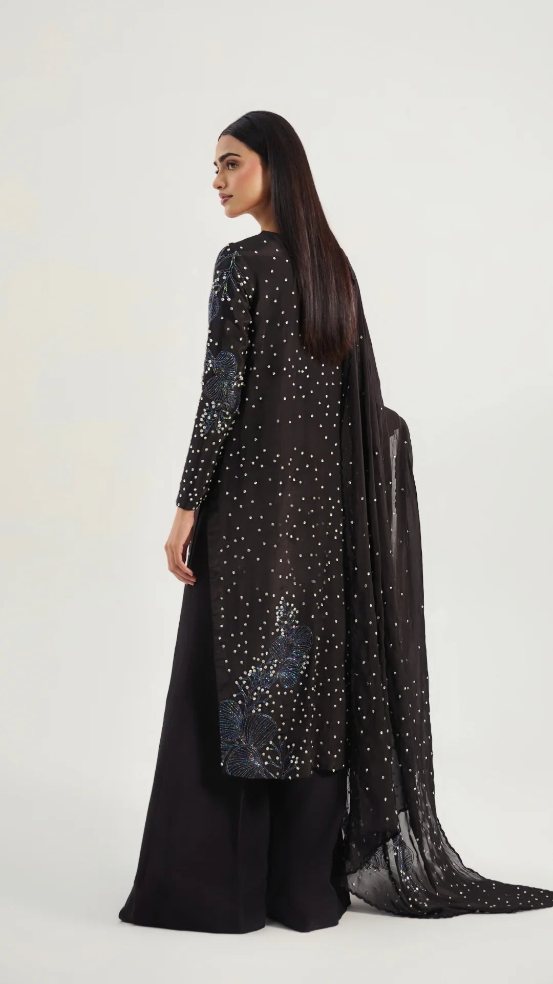 Woman wearing a black outfit with sequin details on a white background