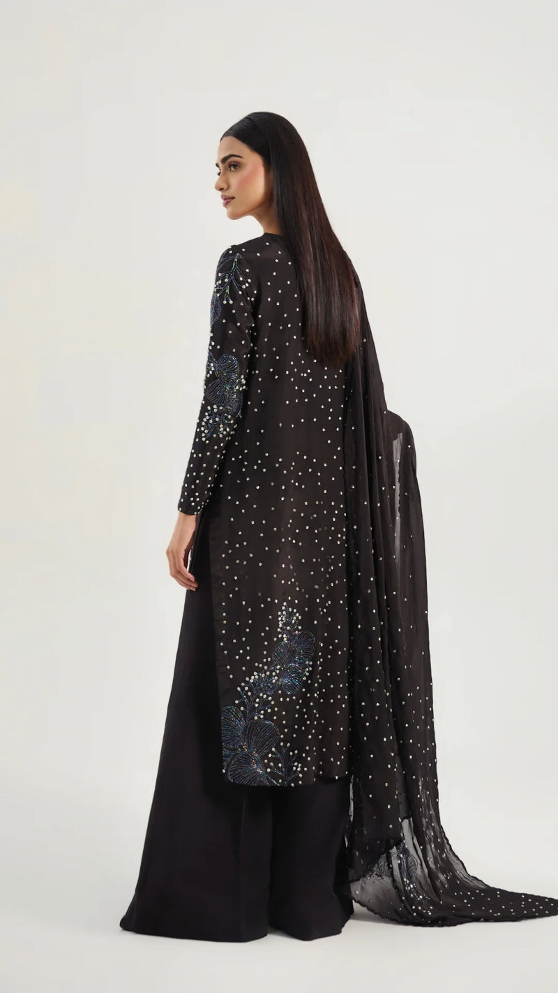 Woman wearing a black outfit with sequin details on a white background