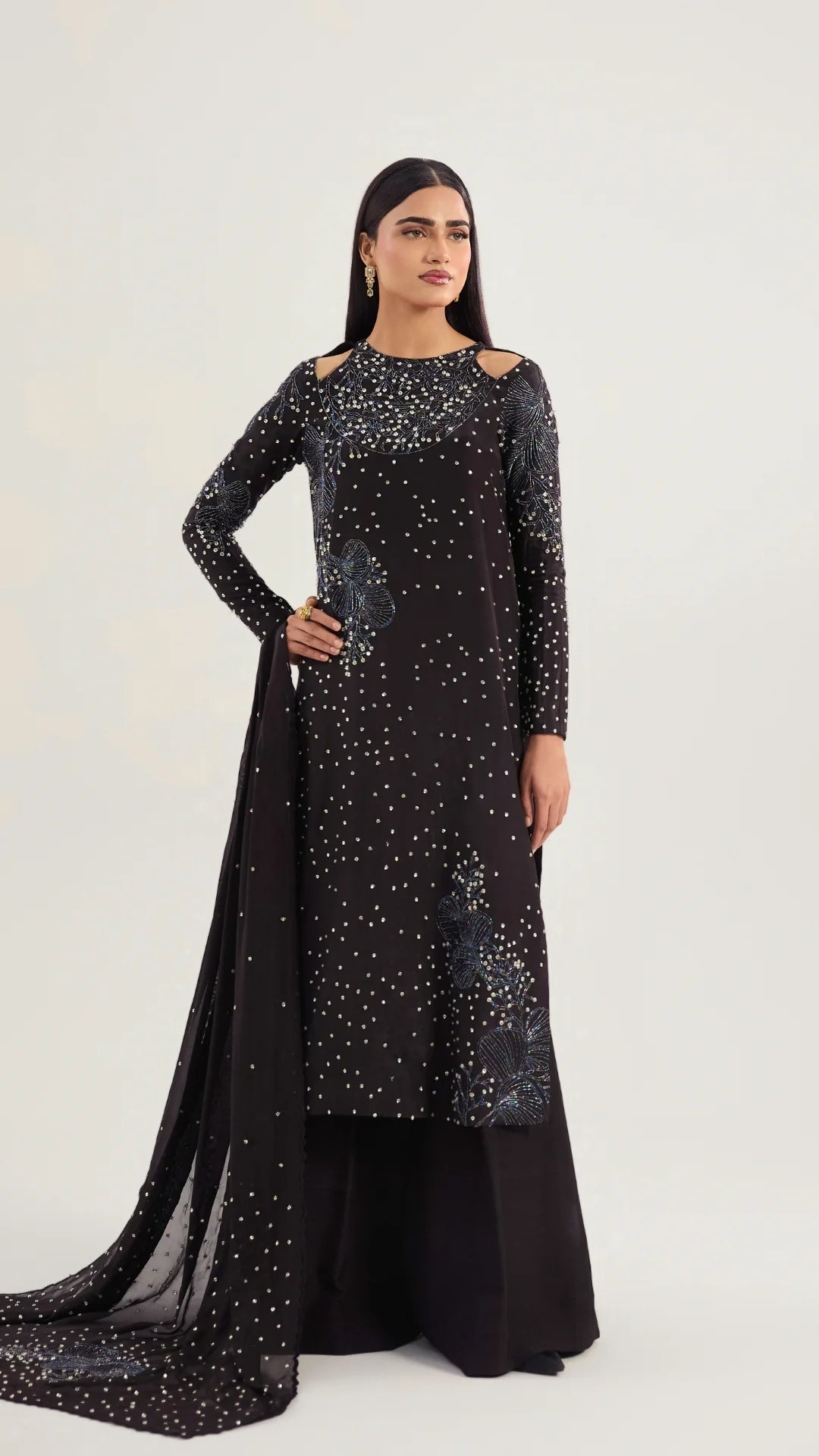 Woman wearing a black outfit with silver embellishments on a white background