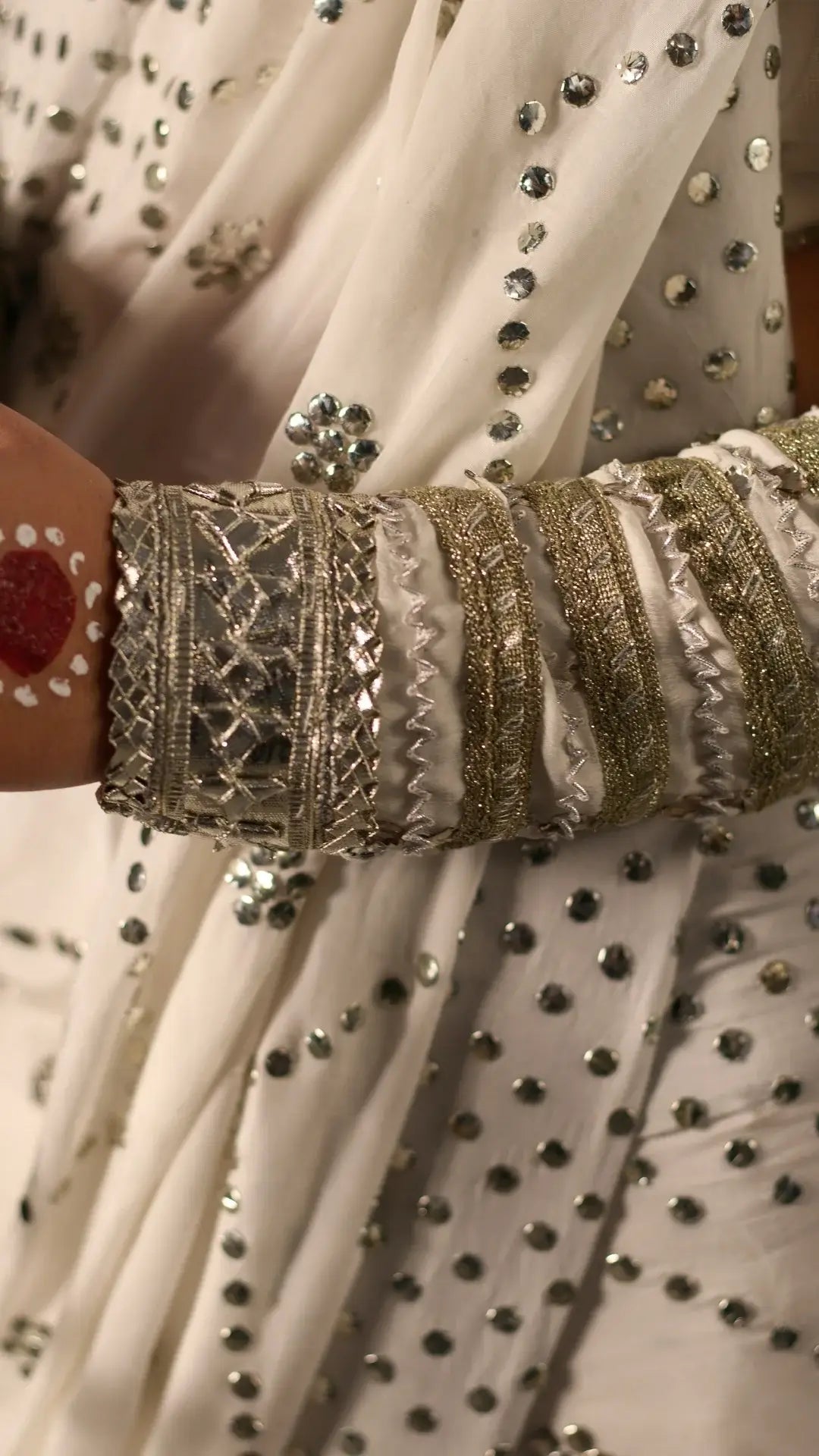 Close-up of a person wearing a traditional outfit with intricate embroidery and jewelry.