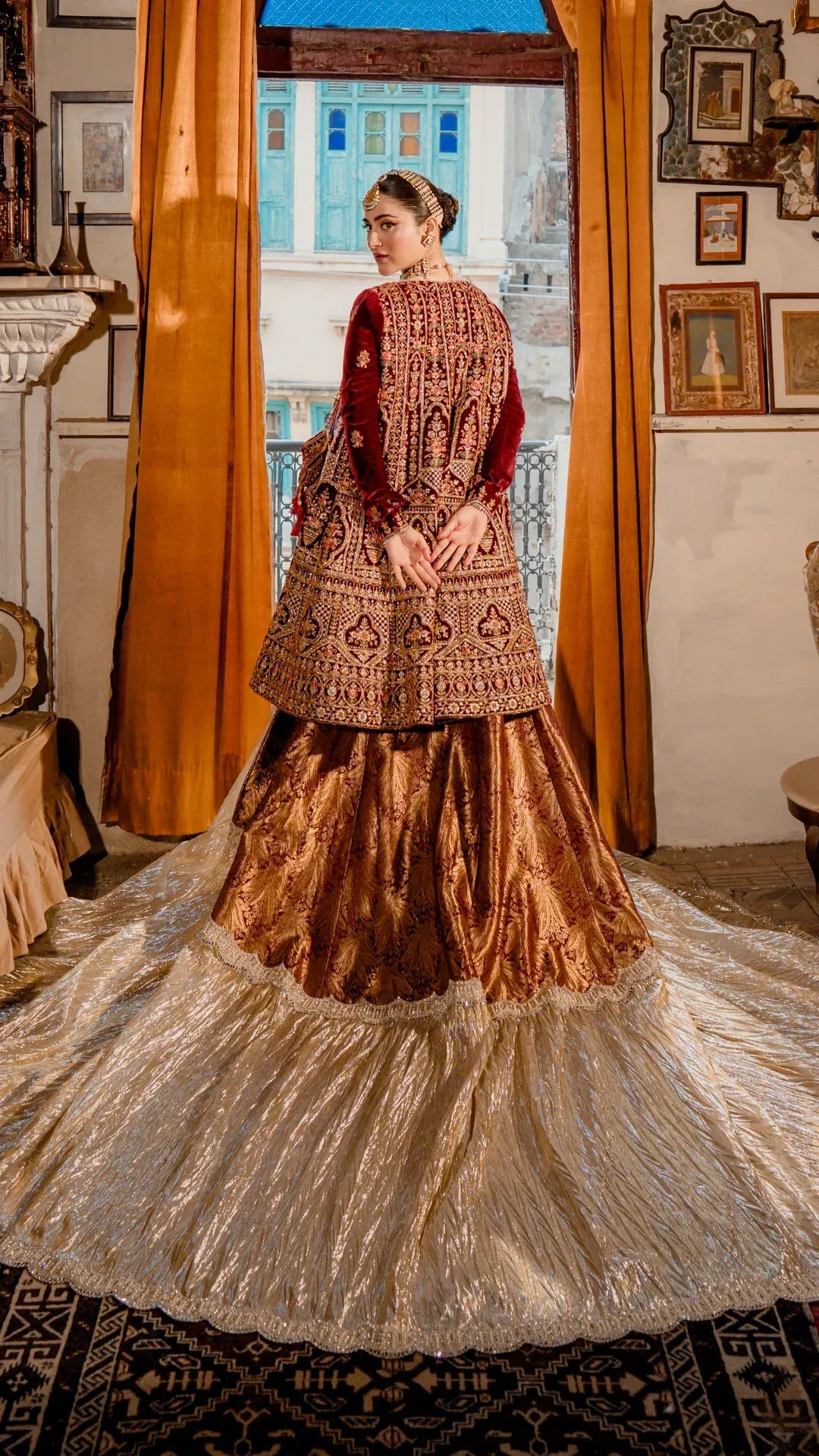 Woman in traditional embroidered outfit standing in a room with decorative elements.