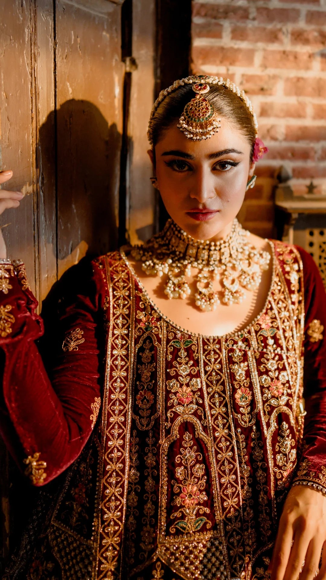 Woman in traditional embroidered outfit with jewelry in a warm-toned setting