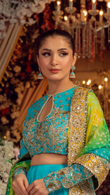 Woman wearing a turquoise and gold embroidered Pakistani formal dress with dupatta, dressed for an elegant event.