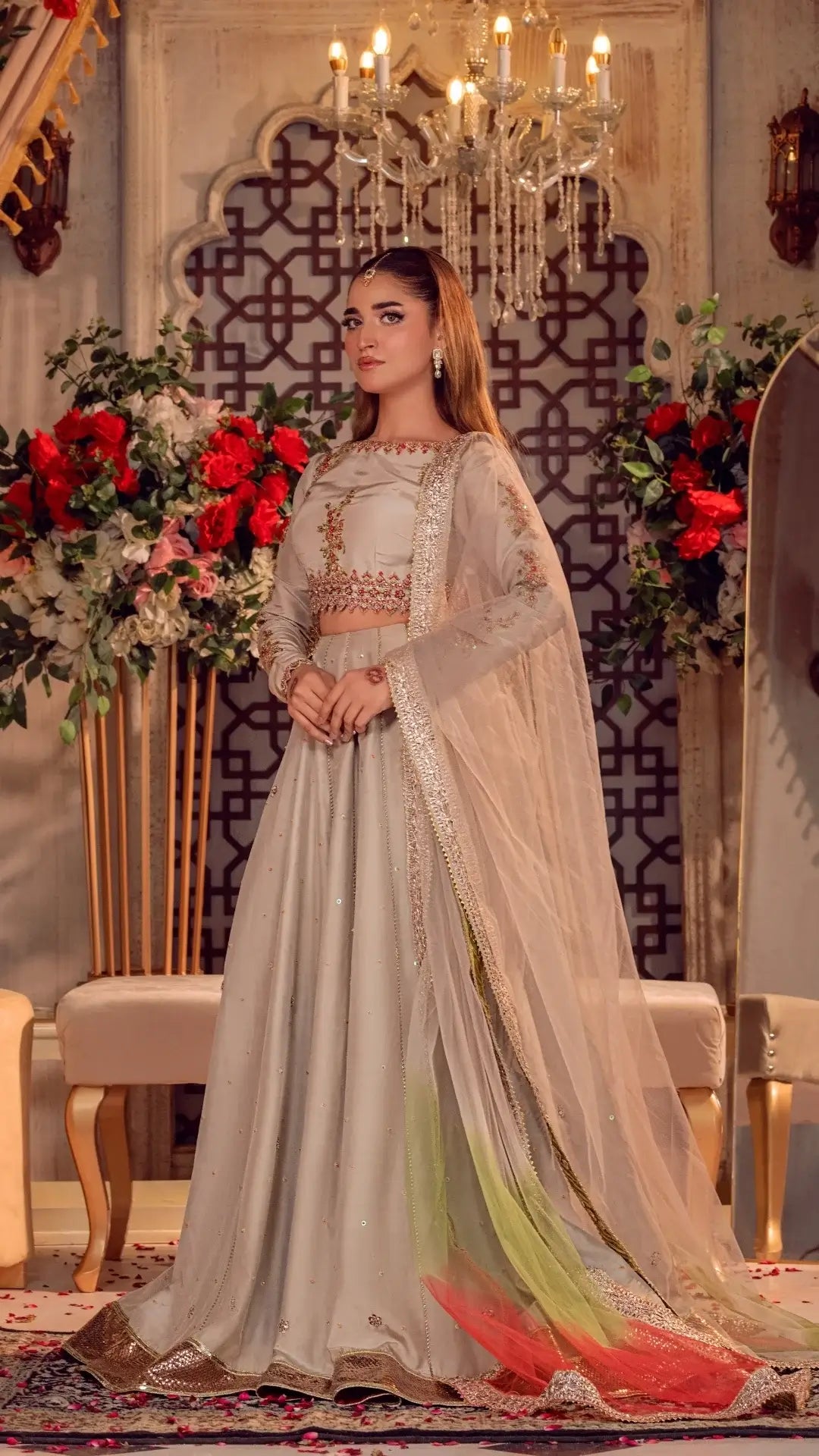 Woman in a traditional outfit with floral decorations and a chandelier in the background