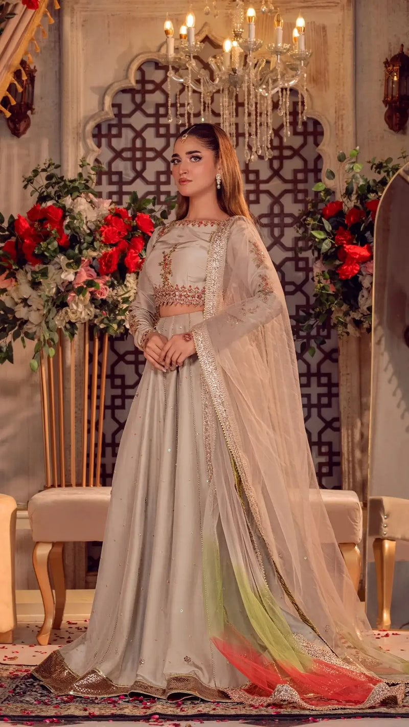 Woman in an elegant formal Pakistani dress with sheer dupatta, floral decor, and chandelier