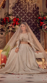 Woman in ivory embellished bridal dress and veil, seated in a floral, elegant setting