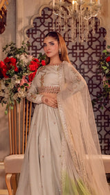 Woman in elegant embroidered Pakistani formal dress with long sheer dupatta in floral setting