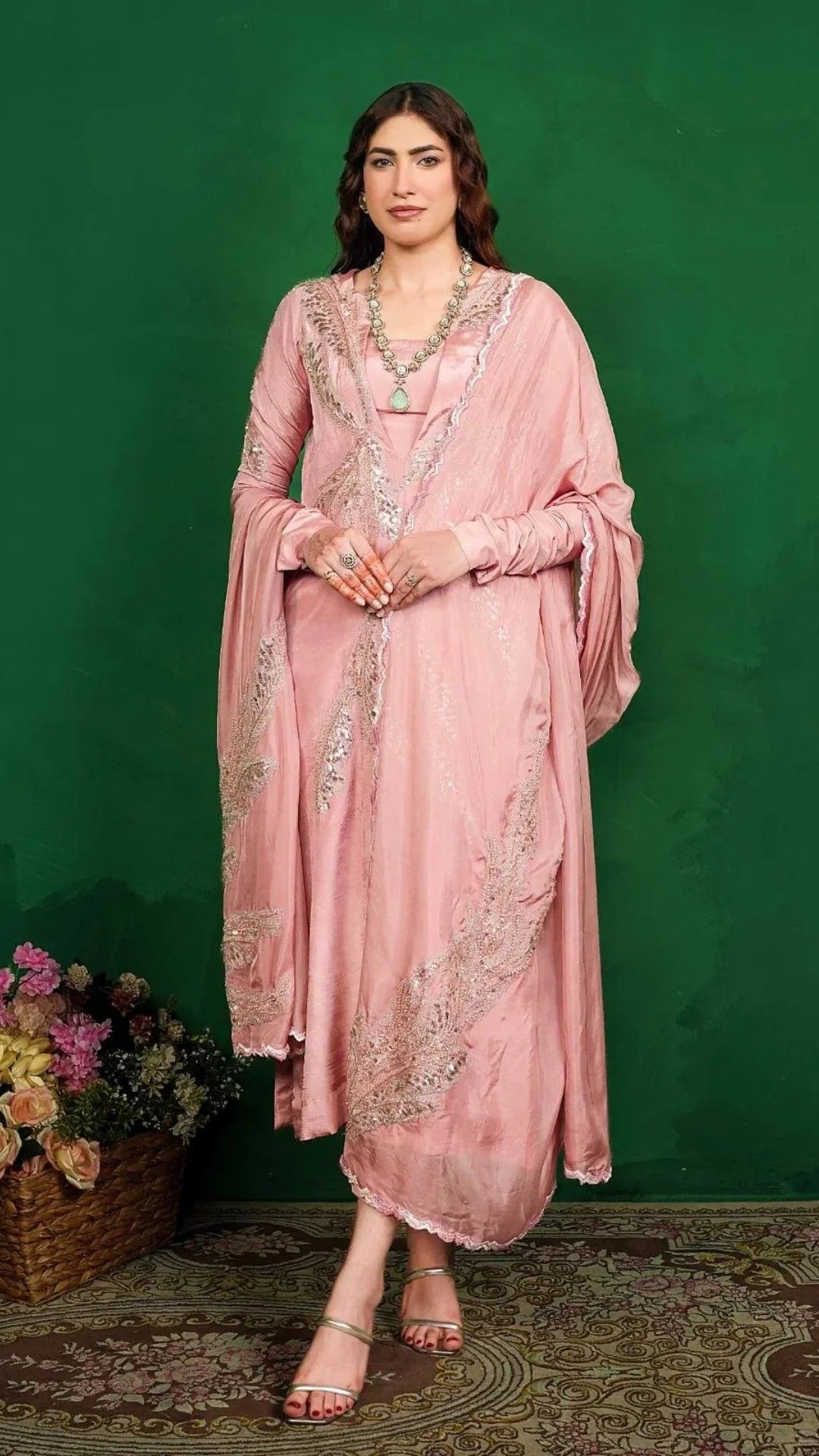 Woman in a pink traditional outfit with intricate designs against a green background