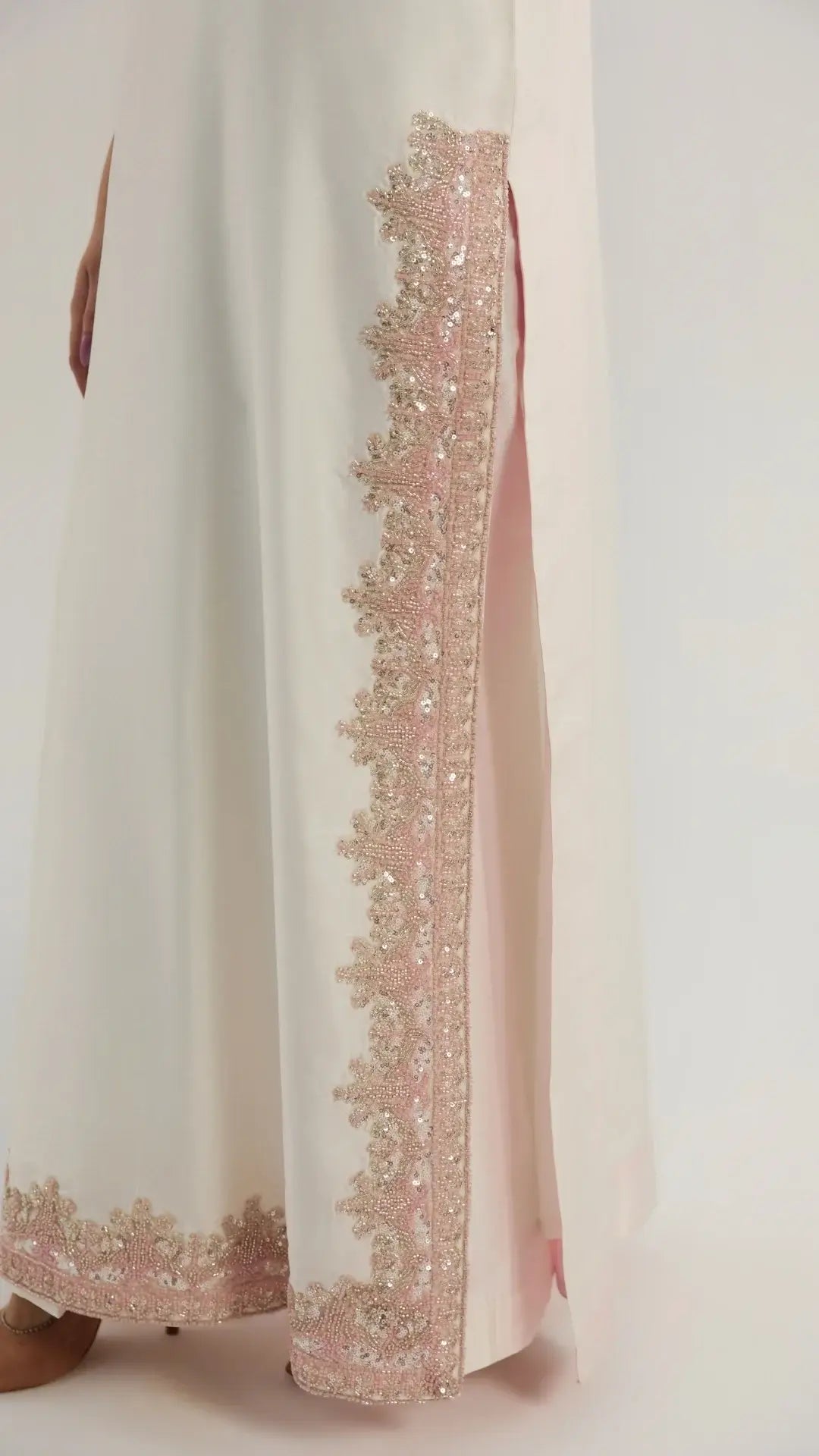 White garment with pink floral embroidery on a white background