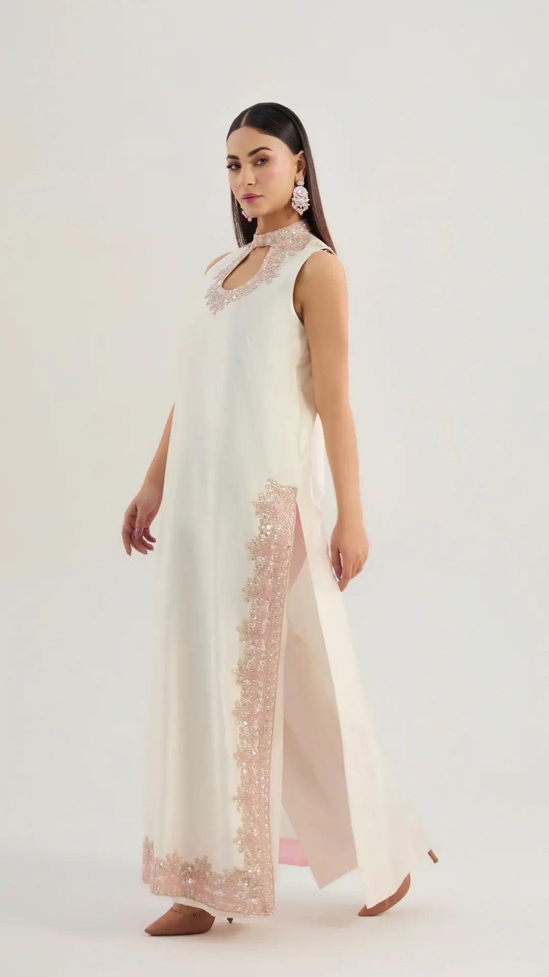 Woman wearing a long, light-colored dress with floral patterns on a white background