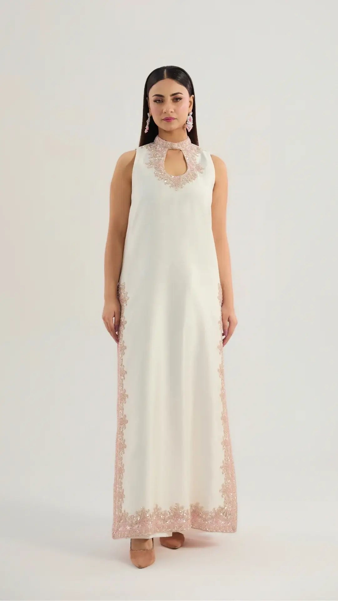 Woman wearing a long, off-white dress with floral lace details on a white background
