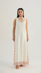 Woman wearing a long, off-white dress with floral lace details on a white background