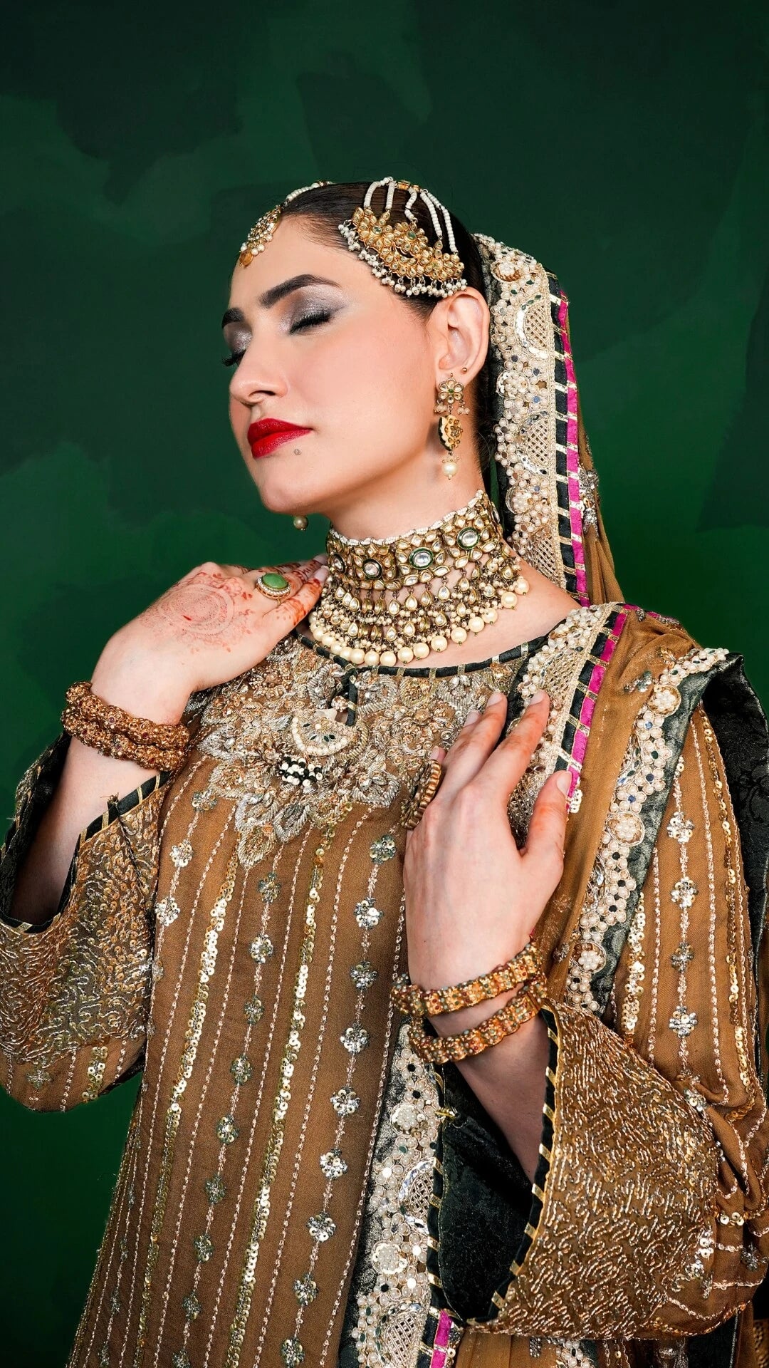 Woman in traditional attire with jewelry against a green background