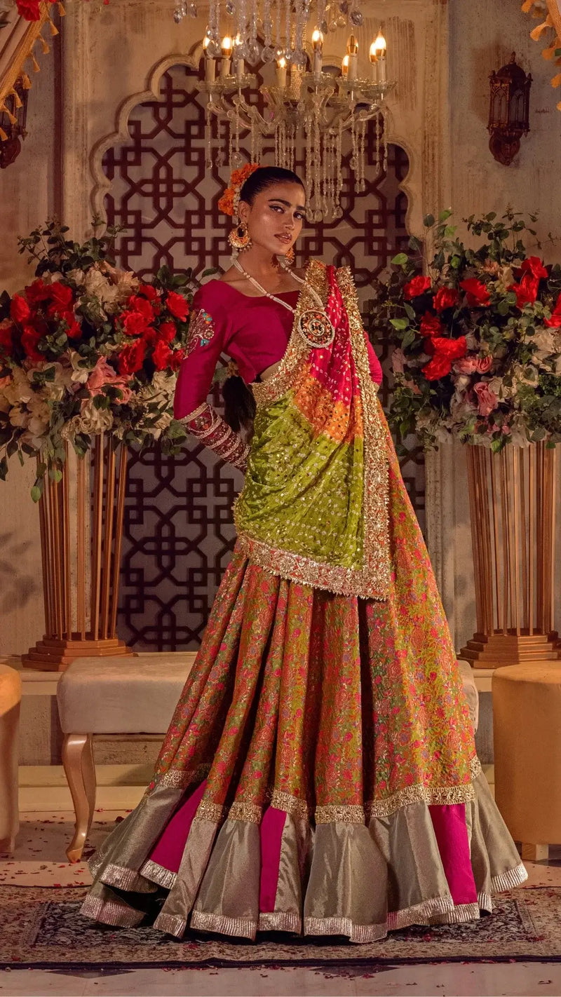 Woman in luxury Pakistani formal dress with detailed embroidery, standing in floral decor