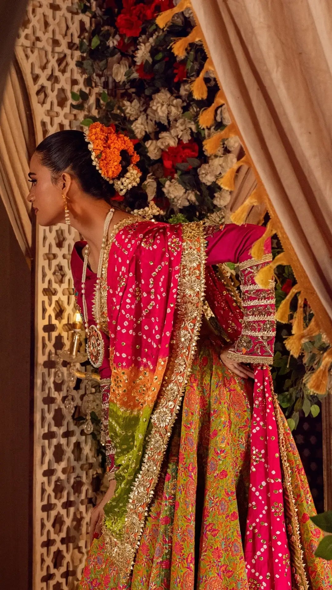 Woman in a colorful traditional outfit with floral decorations in the background