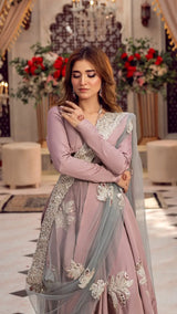Woman in a pastel pink embellished formal Pakistani dress with silver embroidery and dupatta, posing indoors.